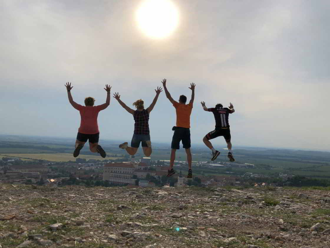 Collectieve jump op de top van de Tanzberg Vier mensen springen omhoog op de Heilige Berg in Mikulov