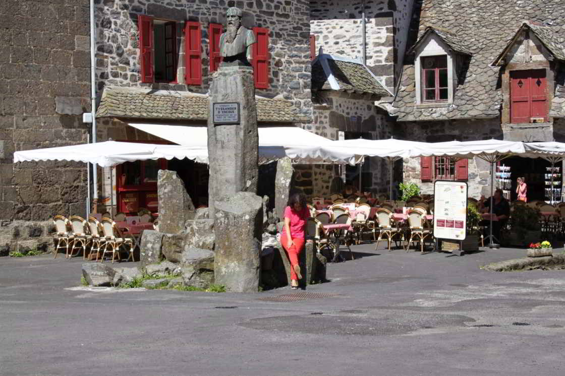 Salers, prachtig stadje in de Auvergne vrouw zit voor een terras in de plaats Salers in Frankrijk